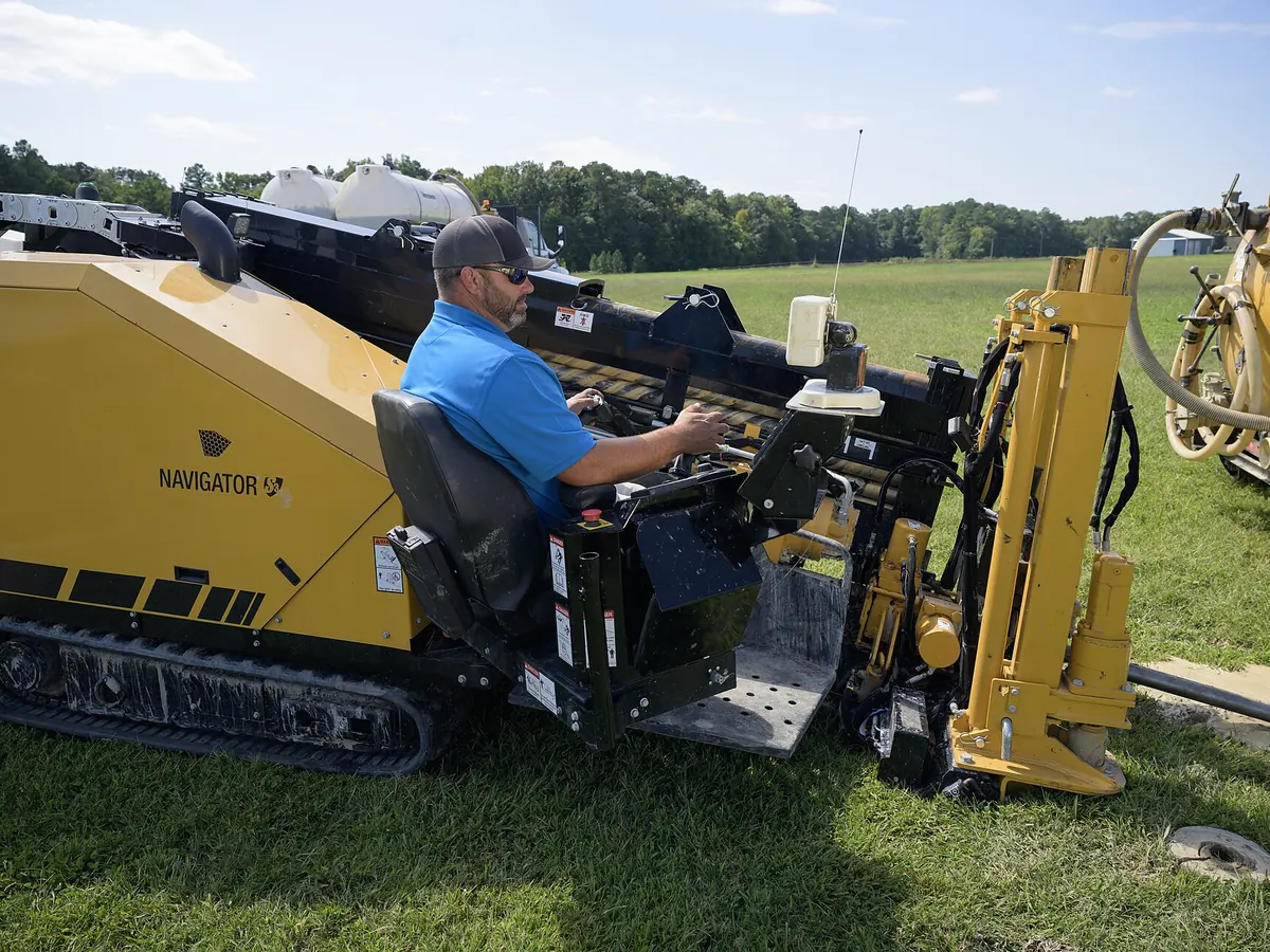 Operator running a horizontal directional drill rig set up on open ground