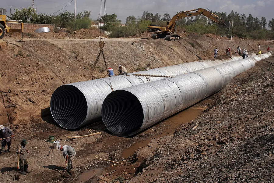 Large-diameter pipe sections staged in an open excavation with equipment above
